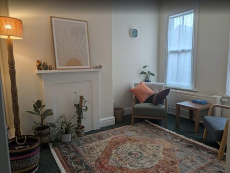 Therapy room at Woodbrooke with rug, plants and armchairs